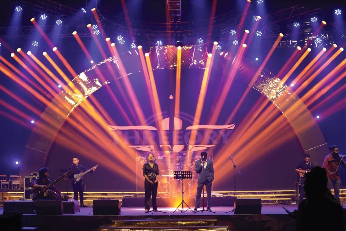 An audience beneath warm stage lights at a live concert
